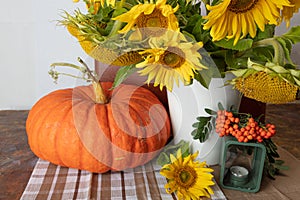 Still life with pumpkin, a bouquet of sunflowers and a white vase, candlesticks and red rowan, hello autumn concept