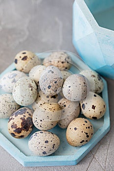 Still life. Quail eggs in a ceramic plate on a textured background. Rustic. Easter celebration concept