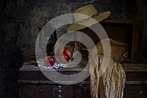 Still Life with red apples and a straw hat on a retro, wooden chest