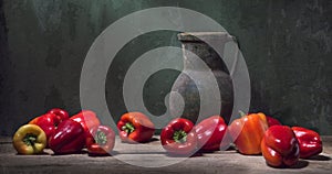 Still life with red bell paprika and a large antique jug on the background of a cracked wall. Art photography.