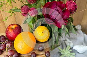 Still life of red peony flowers with fruit on wooden background