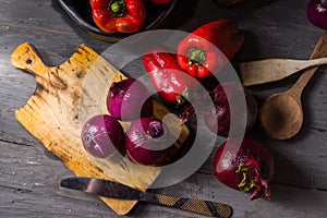 STILL LIFE OF RED PEPPERS WITH ONIONS ON A RUSTIC WOODEN TABLE