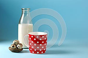 Still life with red, in polka dot, cup of milk, quail eggs and vintage glass bottle