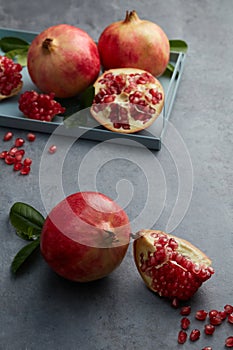 Still life of red pomegranate fruit, seed, half on pastel plate