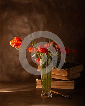 Still life with red poppies and books in the background