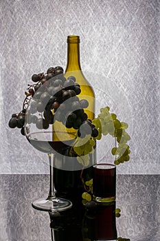 Still life with red wine in a glass and bottle and a bunch of ripe grapes