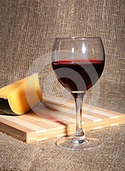 Still life with red wine grapes and chees on wooden table.