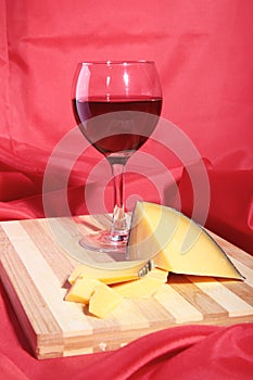 Still life with red wine grapes and chees on wooden table.