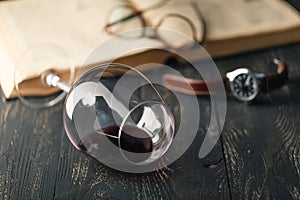 Still life with red wine and old books on the old wooden table in retro style