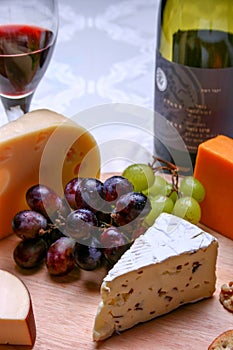 Still life red wine, roquefort cheese, red and green grapes on wooden plate