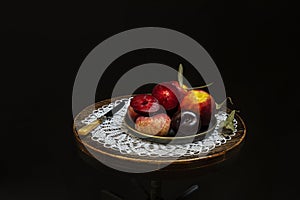 Still life of ripe dark fruits with plums, nectarines on a circular plate