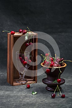 Still life with ripe red cherries with a vase and a glass