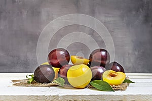 A still life with ripe red and yellow plums