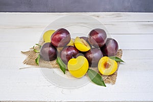 A still life with ripe red and yellow plums with green