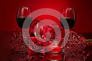 Still life with roses, red hearts and two glasses with wine on red background. Valentine`s Day card