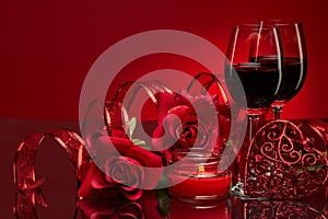 Still life with roses, red hearts and two glasses with wine on a red background. Valentine`s Day card with copy space