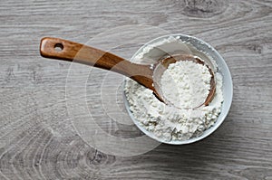 Still life of rural cuisine. White flour in a porcelain bowl with a wooden spoon handmade on a wooden background