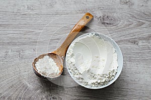 Still life of rural cuisine. White flour in a porcelain bowl with a wooden spoon handmade on a wooden background