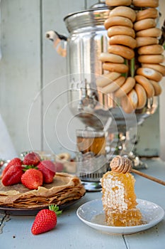 Still life in the Russian tradition for Maslenitsa, pancakes with honey and strawberries, tea from a samovar with bagels