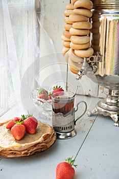 Still life in the Russian tradition for Maslenitsa, pancakes with honey and strawberries, tea from a samovar with bagels