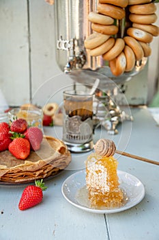 Still life in the Russian tradition for Maslenitsa, pancakes with honey and strawberries, tea from a samovar with bagels