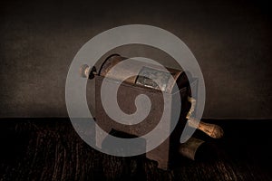 Still life with rustic rusty coffee roaster on vintage grunge background. Side view, cross light