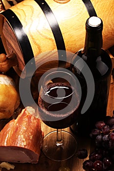 Still life in a rustic style. Grapes on a wooden table with a bottle of wine and meat and cheese. Antipasto and red wine