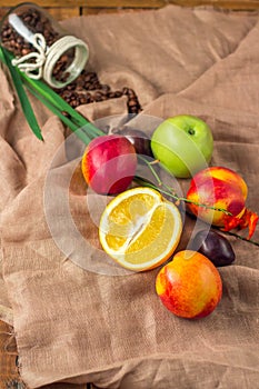 Still life on sackcloth background: apple, peaches, orance, plum