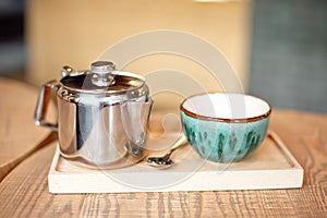 Still life set with cup of tea, teapot and tray on a wooden table in cafe interior