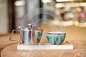 Still life set with cup of tea, teapot and tray on a wooden table in cafe interior