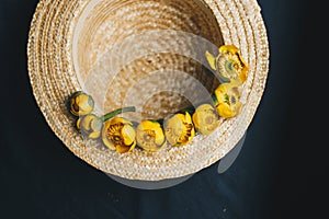 Bouquet of yellow waterlily flower with green leaf. freshly ripped up. In a straw hat. close up on black background of fabric.