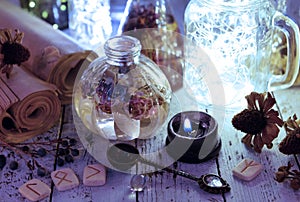 Still life with shining bottles, black candle and runes