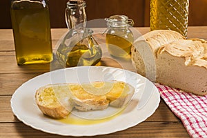 Still life of a slice of bread with olive oil on a white plate