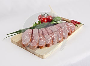 Still life with sliced smoked sausage greens and tomatoes on a white background