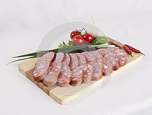 Still life with sliced smoked sausage greens and tomatoes on a white background