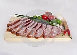 Still life with sliced smoked sausage greens and tomatoes on a white background