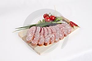 Still life with sliced smoked sausage greens and tomatoes on a white background