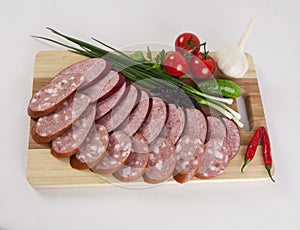 Still life with sliced smoked sausage greens and tomatoes on a white background