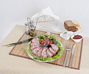 Still life with sliced smoked sausage greens and tomatoes on a white background