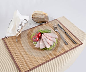 Still life with sliced smoked sausage greens and tomatoes on a white background