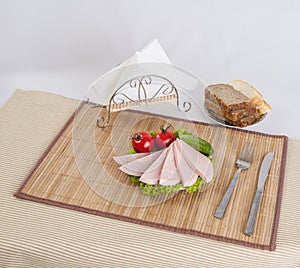 Still life with sliced smoked sausage greens and tomatoes on a white background