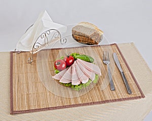 Still life with sliced smoked sausage greens and tomatoes on a white background