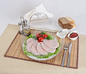 Still life with sliced smoked sausage greens and tomatoes on a white background