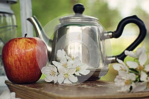 Still life in the spring apple orchard with a teapot and delicate flowers on the table