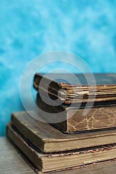 Stack of old books on a wooden table with blue wall background.