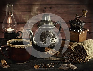 Still life in the style of an old photograph with a coffee grinder, coffee beans with an old lamp and a kettle with a cup with