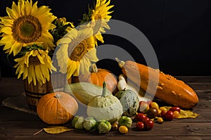 Still life with sunflowers from vegetables on a black background. Thanksgiving and harvest