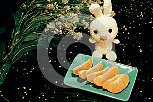 Still life: tangerines, flowers and knitted white rabbit