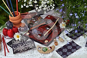 Still life with tarot cards, candle and book on witch table in the garden.