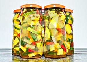 A still life of three glasses of pickled zucchini with some acsessoires arround